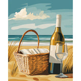 Malen nach Zahlen von Numbered Canvas: Picknickkorb, Weinflasche und Weinglas am Sandstrand mit Meer im Hintergrund.